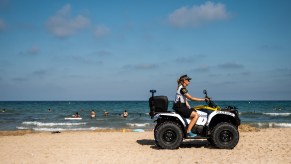 A police officer patrols on an ATV as tourists enjoy a day at the beach