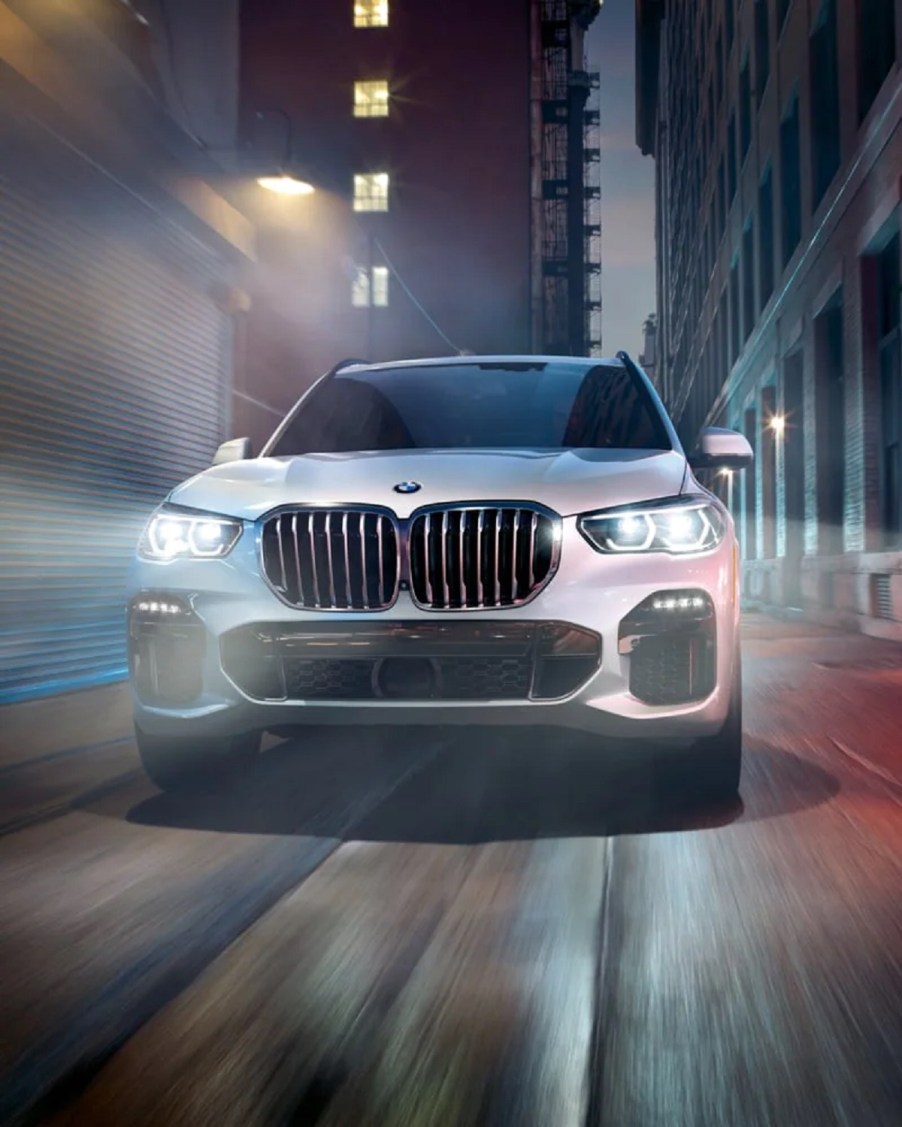 A white 2021 BMW X5 driving through a city.