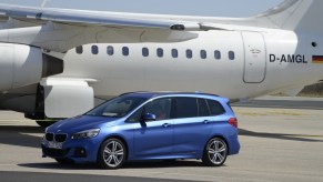 BMW minivan parked next to a plane