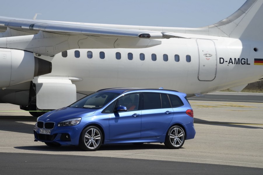 BMW minivan parked next to a plane