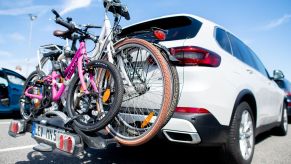 A bike rack with bicycles on it using a white SUV.