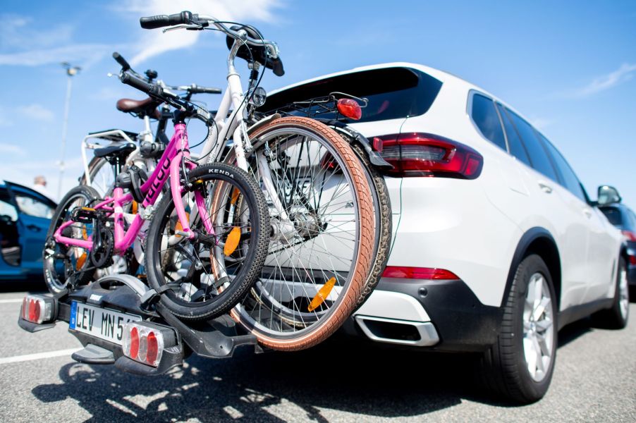 A bike rack with bicycles on it using a white SUV.