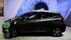 A black Chevy Bolt sits charging in front of a blue and black background.