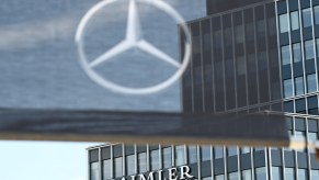 A Daimler logo is attached to a building at the headquarters of the Stuttgart-based car manufacturer, and a flag with a Mercedes-Benz star hangs in the foreground