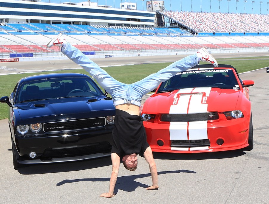 Michal 'Misha Furmanczyk from the show 'Absinthe does a handstand in front of a Dodge Challenger SRT8 392 and a Ford Mustang Shelby GT350 in April 2013 in Las Vegas, Nevada