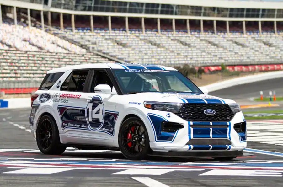 The white-with-blue-stripes Ford Performance Racing School Explorer ST on a racetrack