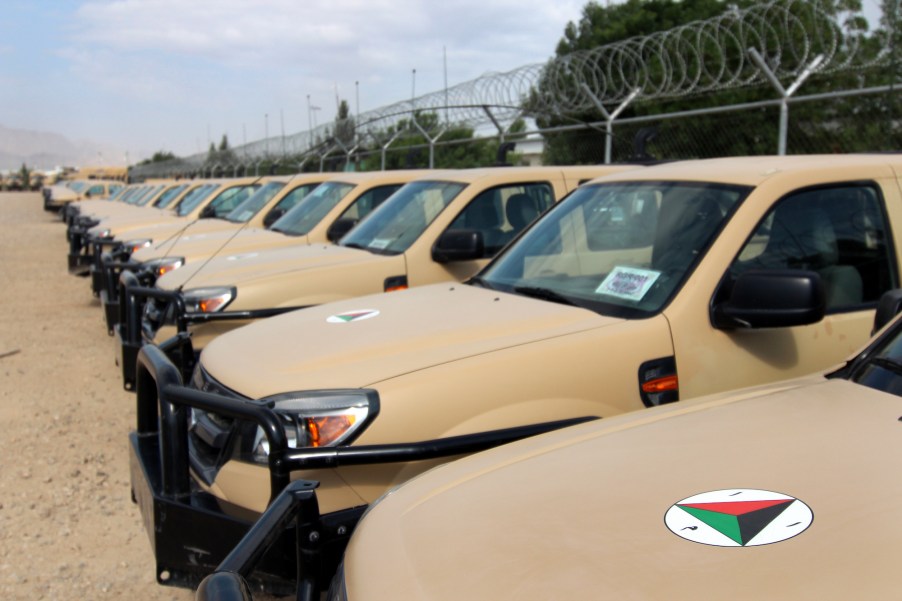 A row of Ford Ranger trucks parked along a barbwire fence in Afghanistan