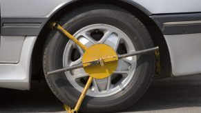 A yellow wheel clamp on a car tire.