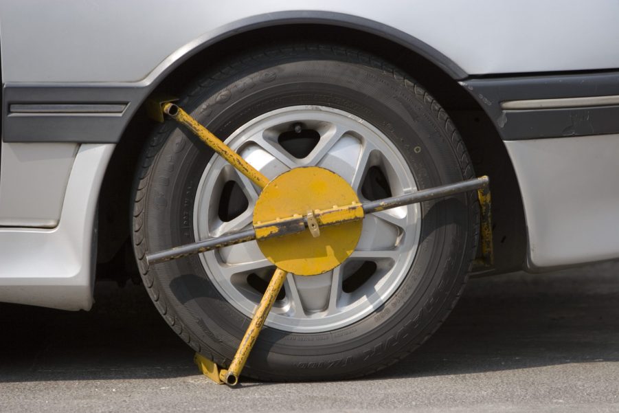 A yellow wheel clamp on a car tire.