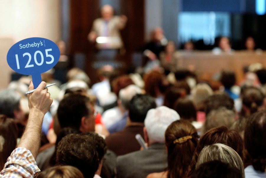 An auction bidder raises their card at a Sotheby's auction