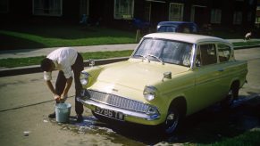 Man Washes His Classic Ford Anglia Car