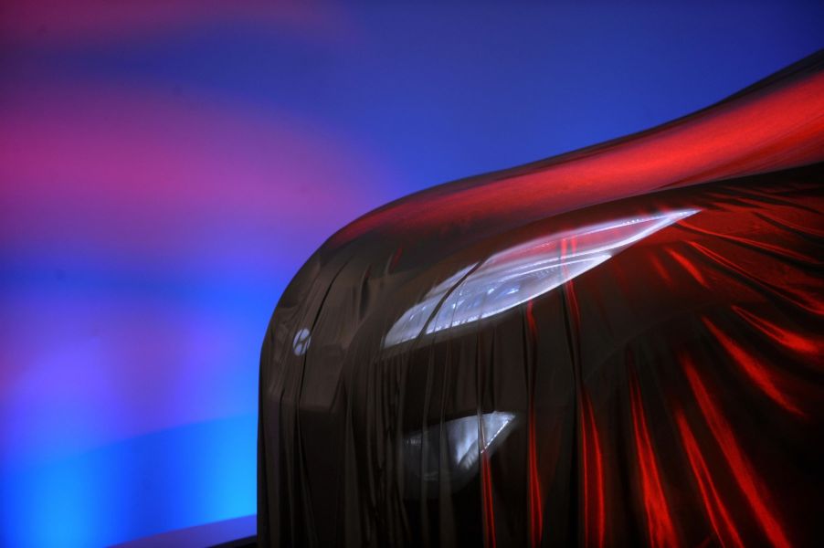 A headlight covered in a veil that gives off a red glow with a blue and pink background.