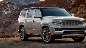 The Jeep Grand Wagoneer luxury SUV parked on a dirt trails near grassy hills and mountains