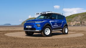 The lifted, blue Kia Beach EV with surfboards mounted on the roof