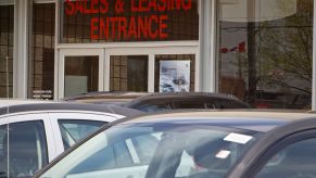 Sales and Leasing Entrance is written above a door with cars sitting in front of it.