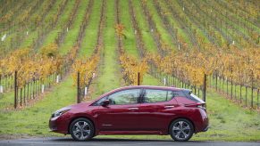 A red Nissan Leaf photographed in profile in a field