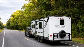 a North Trail travel trailer being pulled on a road in the forest