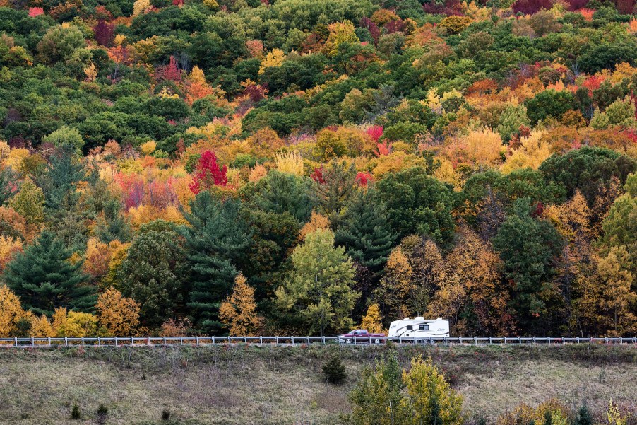 A pickup driving through VT with an RV camper attached