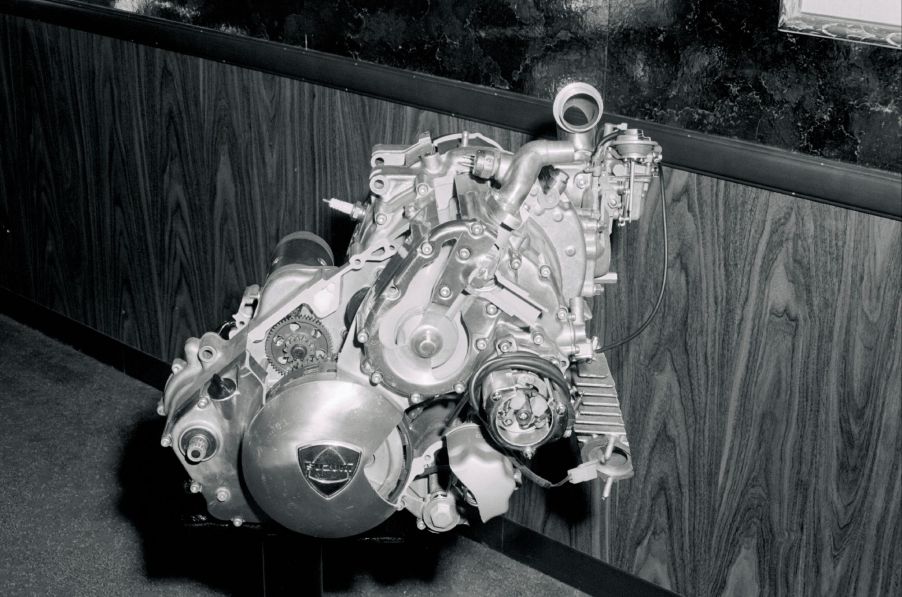 A black and white picture of a rotary engine with a wooden backdrop.