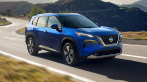 A blue 2021 Nissan Rogue driving on the road