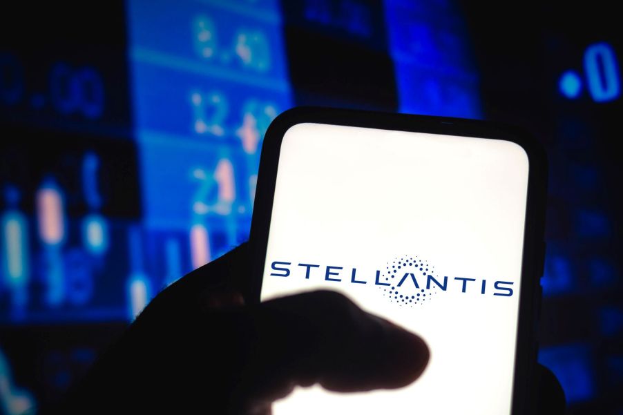 The Stellantis logo on a smartphone with a background of numbers and prices