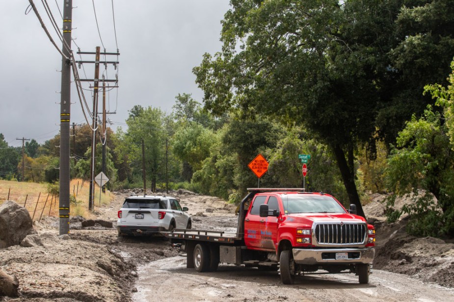 A tow truck rescuing a Ford Explorer in the mud