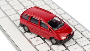 A tiny red minivan toy placed on top of an Apple keyboard