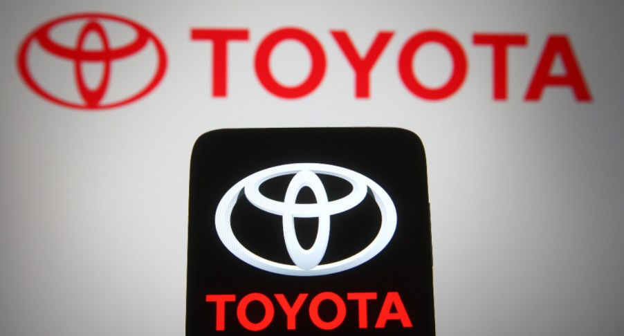 In this photo illustration, a Toyota logo seen displayed on a smartphone and a pc screen.