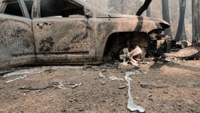 A burned vehicle and destroyed forest road from the Dixie Fire worsened by climate change