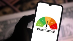 In this photo illustration a businessman holds his smartphone showing a graph with the credit score