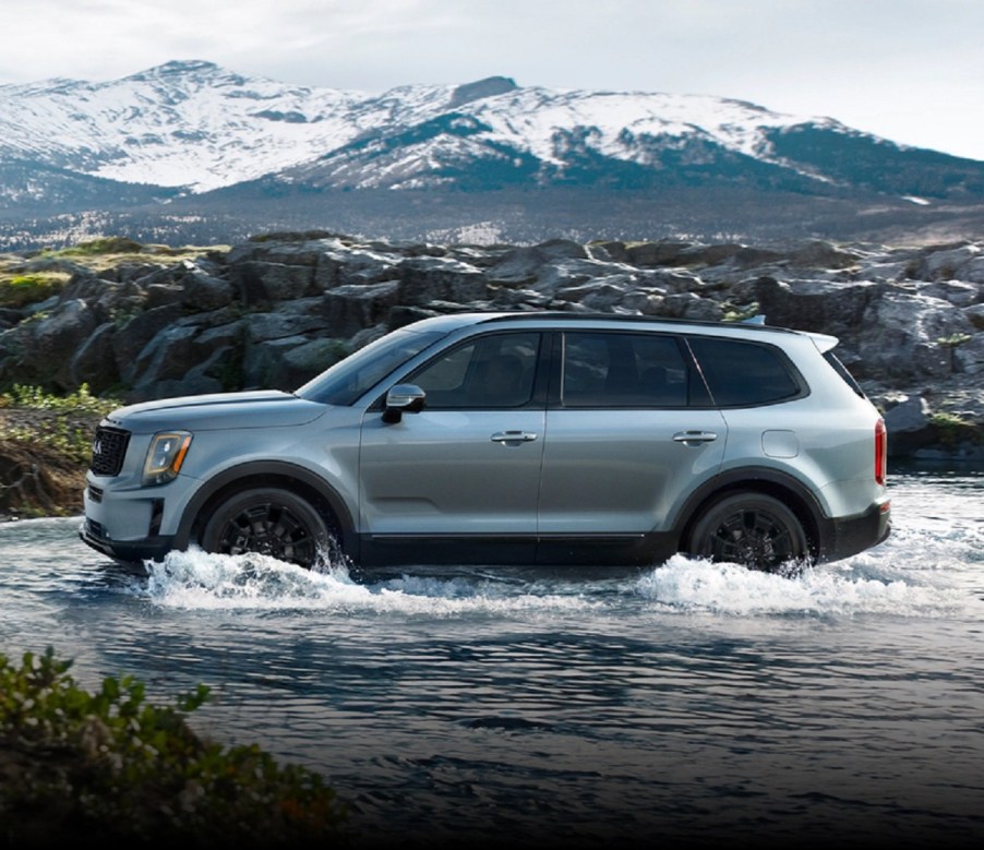 A silver 2021 Kia Telluride splashes across a river.