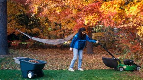 Woman cutting the lawn in autumn