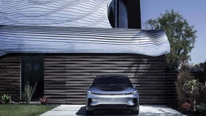 A silver Faraday FF 91 parked in front of a garage.