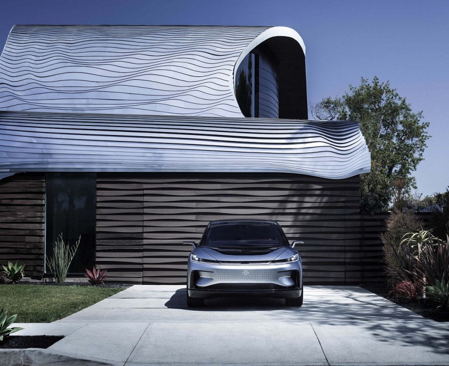 A silver Faraday FF 91 parked in front of a garage.