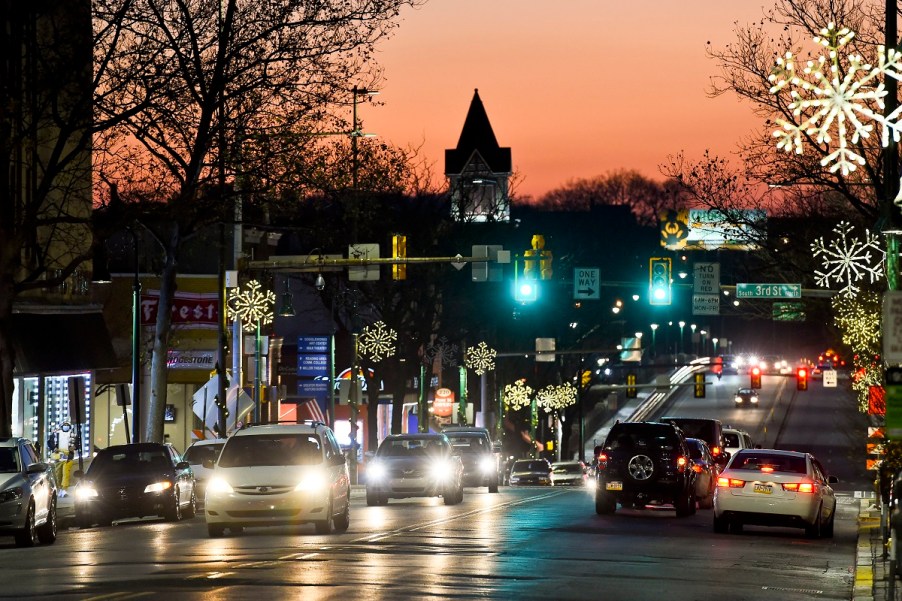 Cars with their headlights on driving through town.