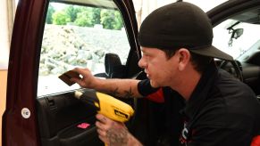 A man performing a window tinting service with a heat gun