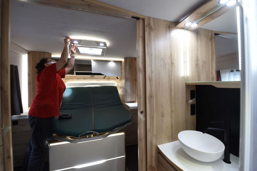 A woman checking the lights in a Le Voyageur motorhome bathroom in France