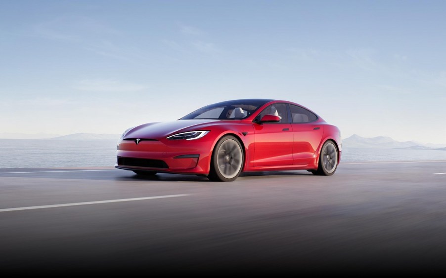 A red 2021 Tesla Model S driving down a highway.