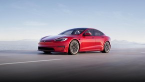 A red 2021 Tesla Model S driving down a highway.