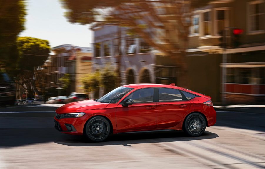 A red 2022 Honda Civic hatchback shot in profile on a city street