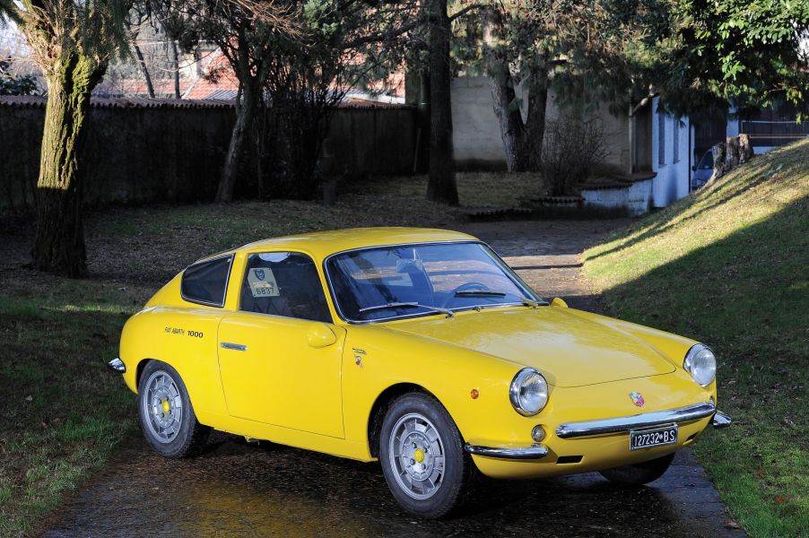 A yellow 1963 Fiat-Abarth Monomille GT parked on a grassy path