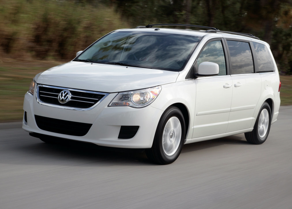 A white 2009 volkswagen routan drives on a road during the day