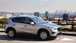 A silver 2014 Mazda CX-5 parked on a road overlooking a city skyline