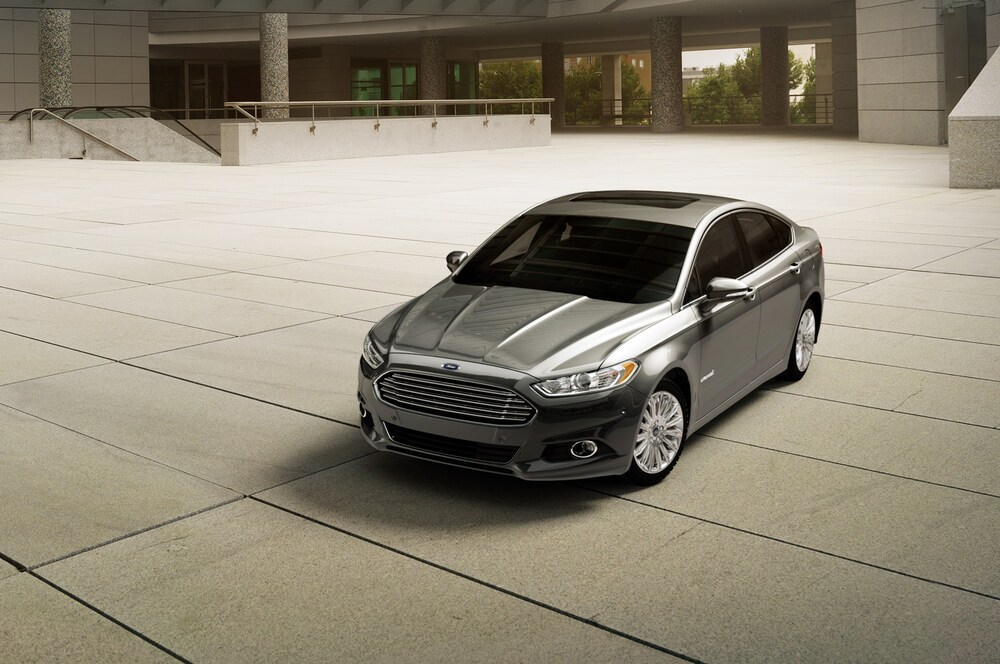 A grey 2015 Ford Fusion Hybrid parked near a building