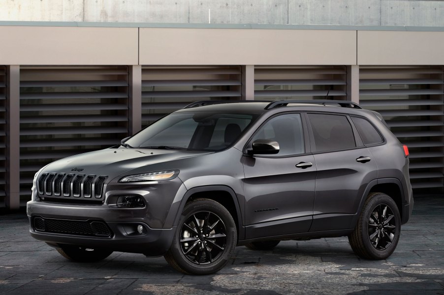 A gray 2015 Jeep Cherokee parked outside by a wall