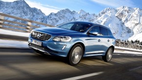 A 2017 Volvo XC60 T6 AWD luxury compact SUV travels on a highway past snow-capped mountains