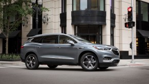 A dark-silver 2021 Buick Enclave midsize three-row SUV at a city intersection