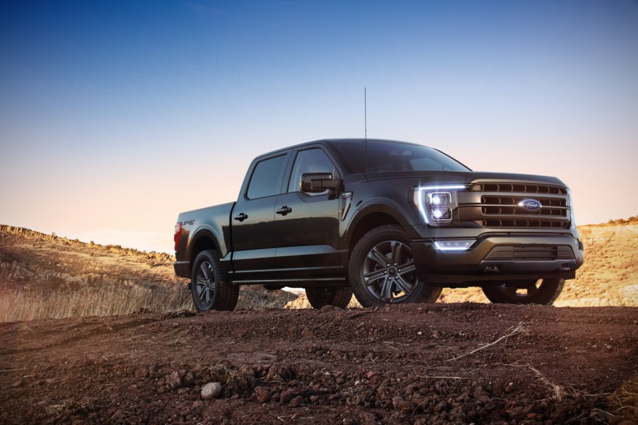 A black 2021 Ford F-150 Lariat Sport parked on a dirt hill at night