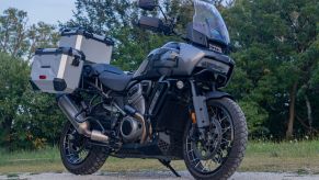 A low-angle view of a gray-and-black 2021 Harley-Davidson Pan America 1250 Special by a forest