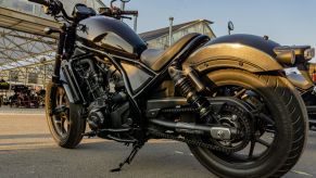 A low-angle left side 3/4 view of a black 2021 Honda Rebel 1100 DCT